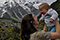 Image of a female holding up a baby and smiling with snowy mountains in the background